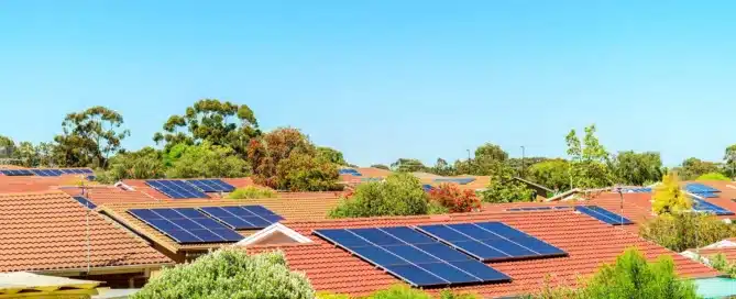 Tiled roofs with solar panels. "A New Roof: The Best Investment You Will Ever Make." Sunny suburban neighborhood.