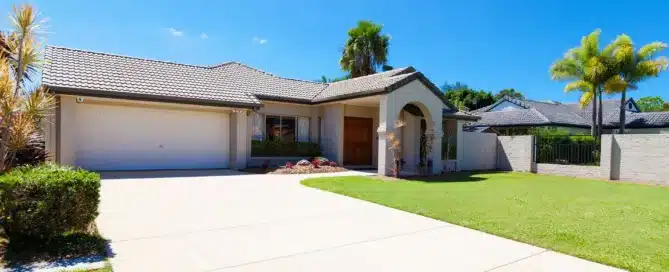 House with a "long-lasting roof". Tile roof on a modern home with manicured lawn and driveway under a bright blue sky.