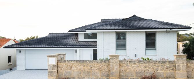 Modern white brick house with black tile roof. Stone wall and brick paving at the front. "Paul Richardson Photography.