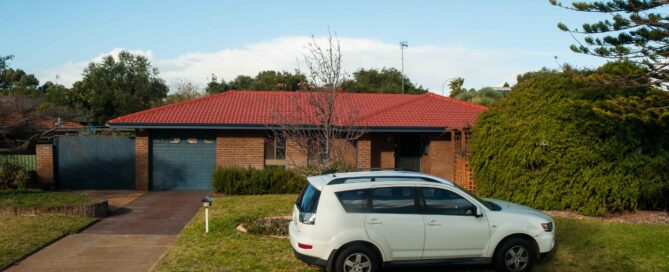 Brick house with red tile roof and white SUV in driveway. "Paul Richardson Photography" credit.