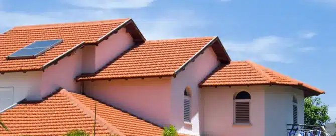 Orange tiled roof with a solar panel on a white house. "Roofing Safety" hazards.