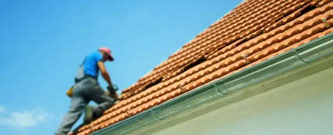 Roofer repairing damaged terracotta tile roof. "Should You Get Your Roof Repaired Before You Sell.