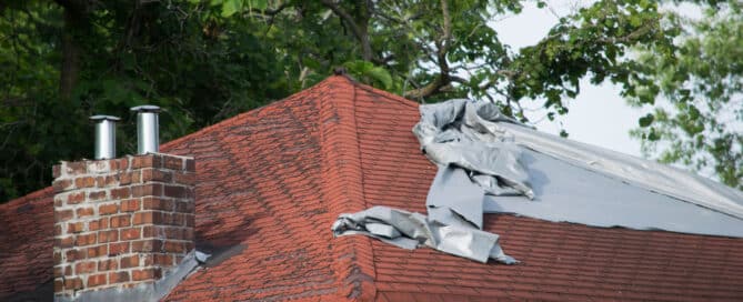 Damaged roof with missing shingles covered by a tarp. "Tell-Tale Signs that Your Roof Needs Repairing.