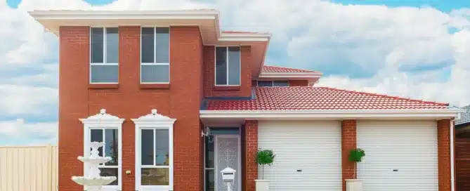 Red brick two-story home with a "red tile roof" and white trim. Double garage and fountain.